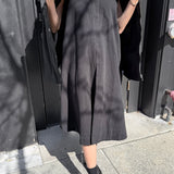 Person wearing a black dress standing against a dark background