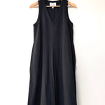 Black sleeveless dress on a hanger against a white background