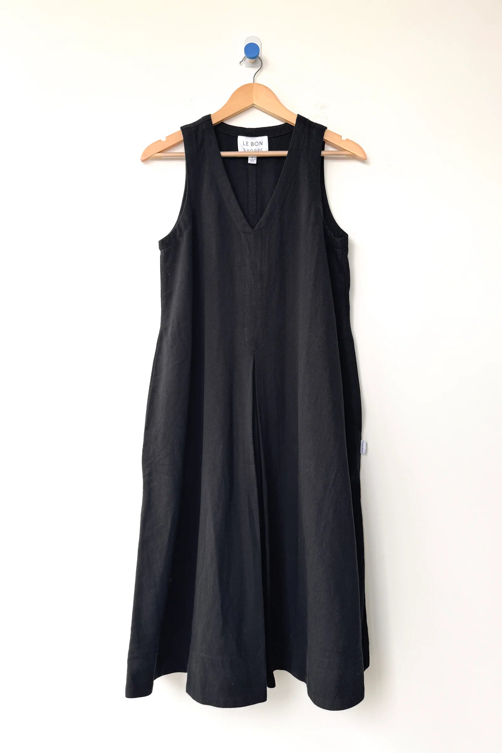 Black sleeveless dress on a hanger against a white background