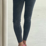 Person wearing dark gray leggings and pink shoes on a light wooden floor.
