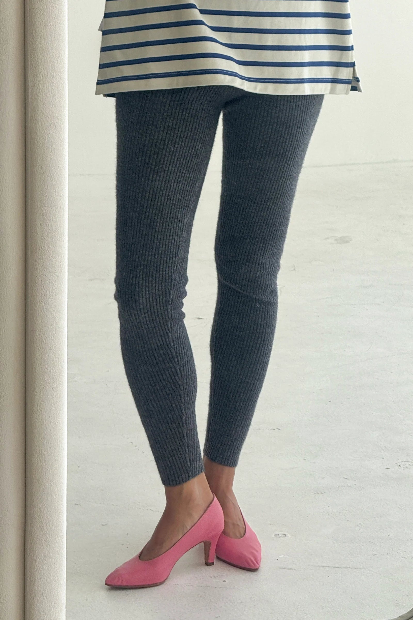 Person wearing dark gray leggings and pink shoes on a light wooden floor.