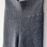 Gray ribbed knit sweater hanging on a rack with tags.