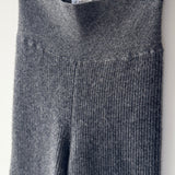 Gray ribbed knit sweater hanging on a rack with tags.