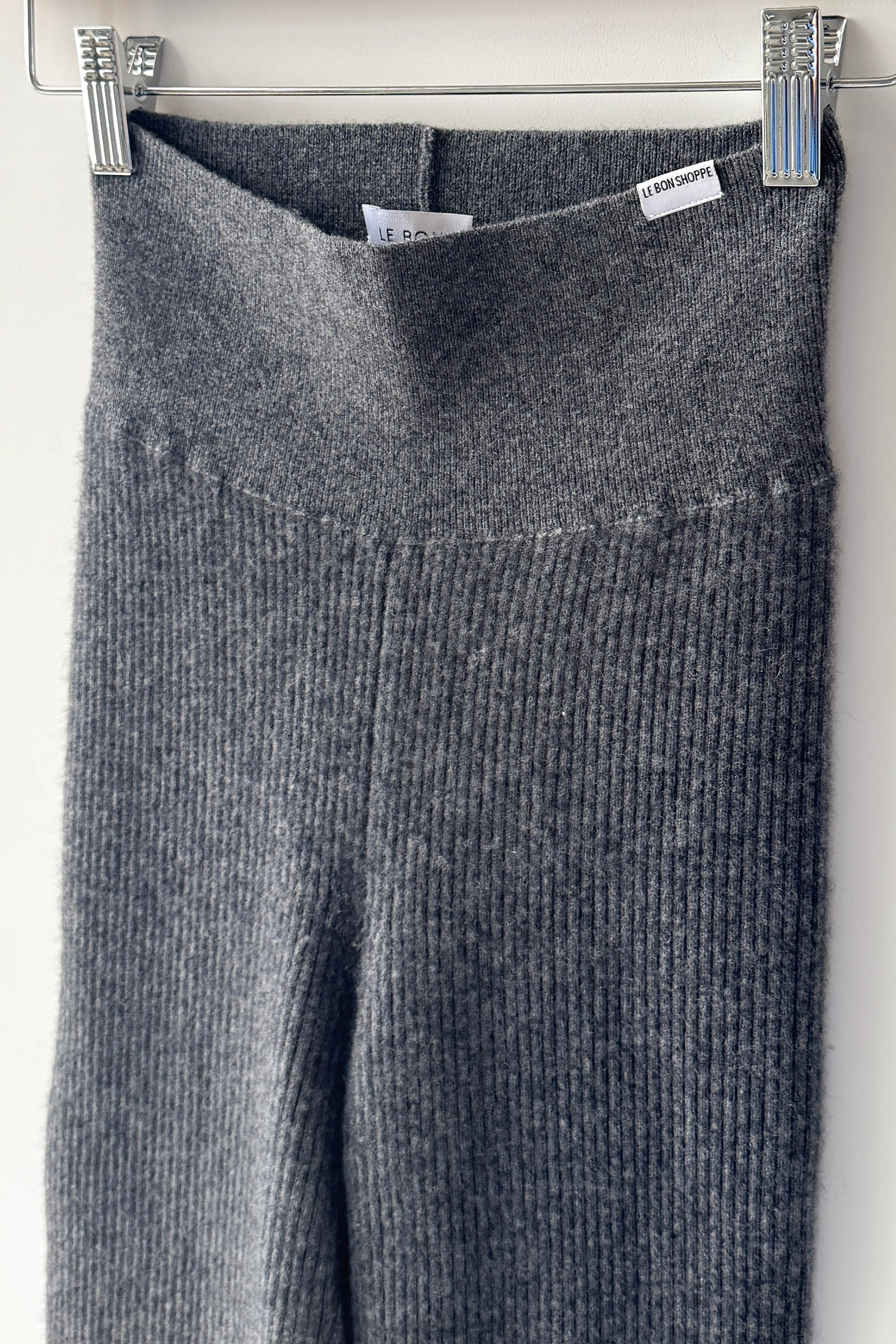 Gray ribbed knit sweater hanging on a rack with tags.