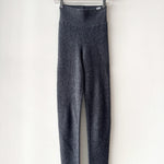 Gray leggings hanging on a wooden hanger against a white background