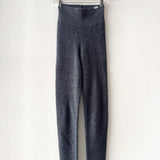 Gray leggings hanging on a wooden hanger against a white background