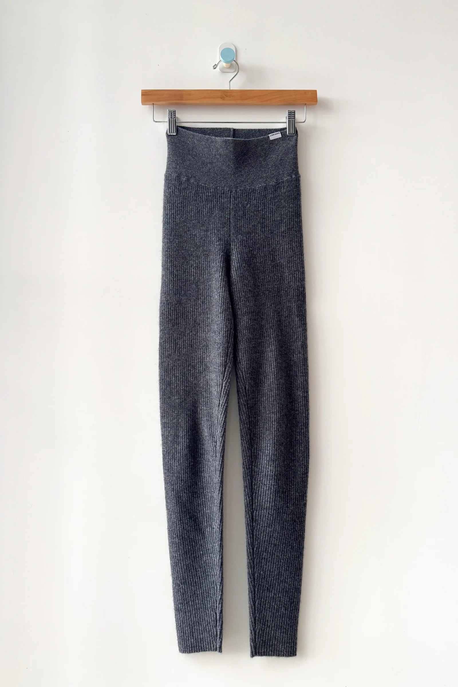 Gray leggings hanging on a wooden hanger against a white background