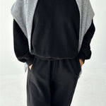 Person wearing a black outfit with a gray cardigan on a white background