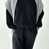 Person wearing a black outfit with a gray cardigan on a white background