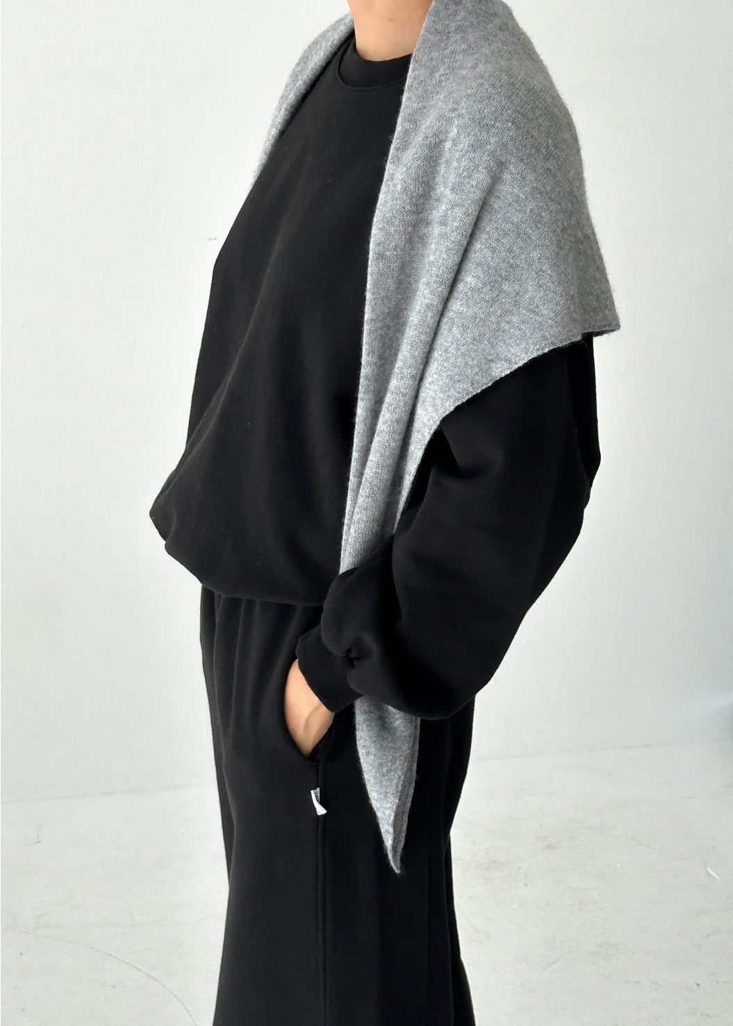 Person wearing a black outfit with a gray cardigan on a white background