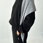 Person wearing a black outfit with a gray cardigan on a white background