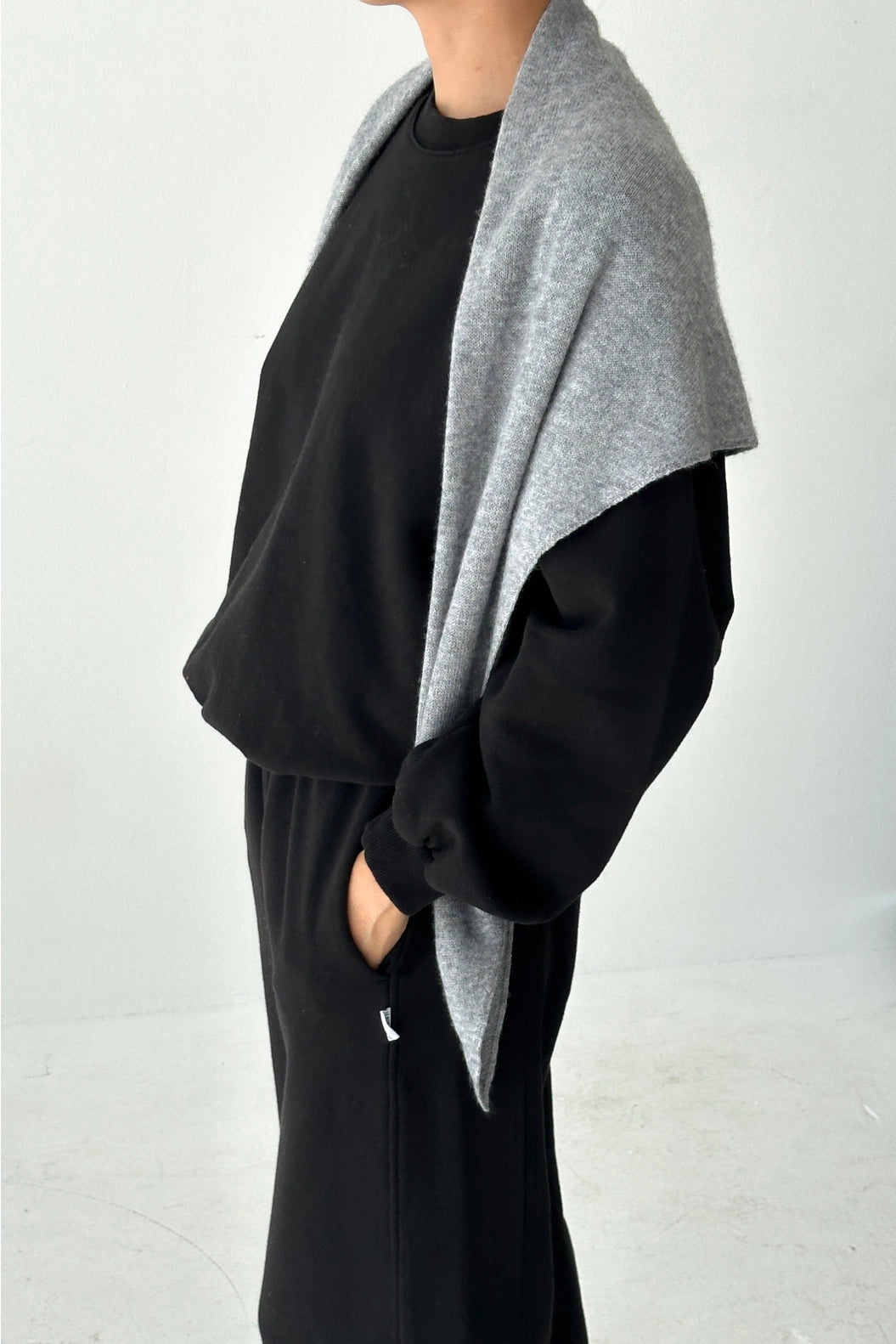 Person wearing a black outfit with a gray cardigan on a white background