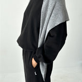 Person wearing a black outfit with a gray cardigan on a white background