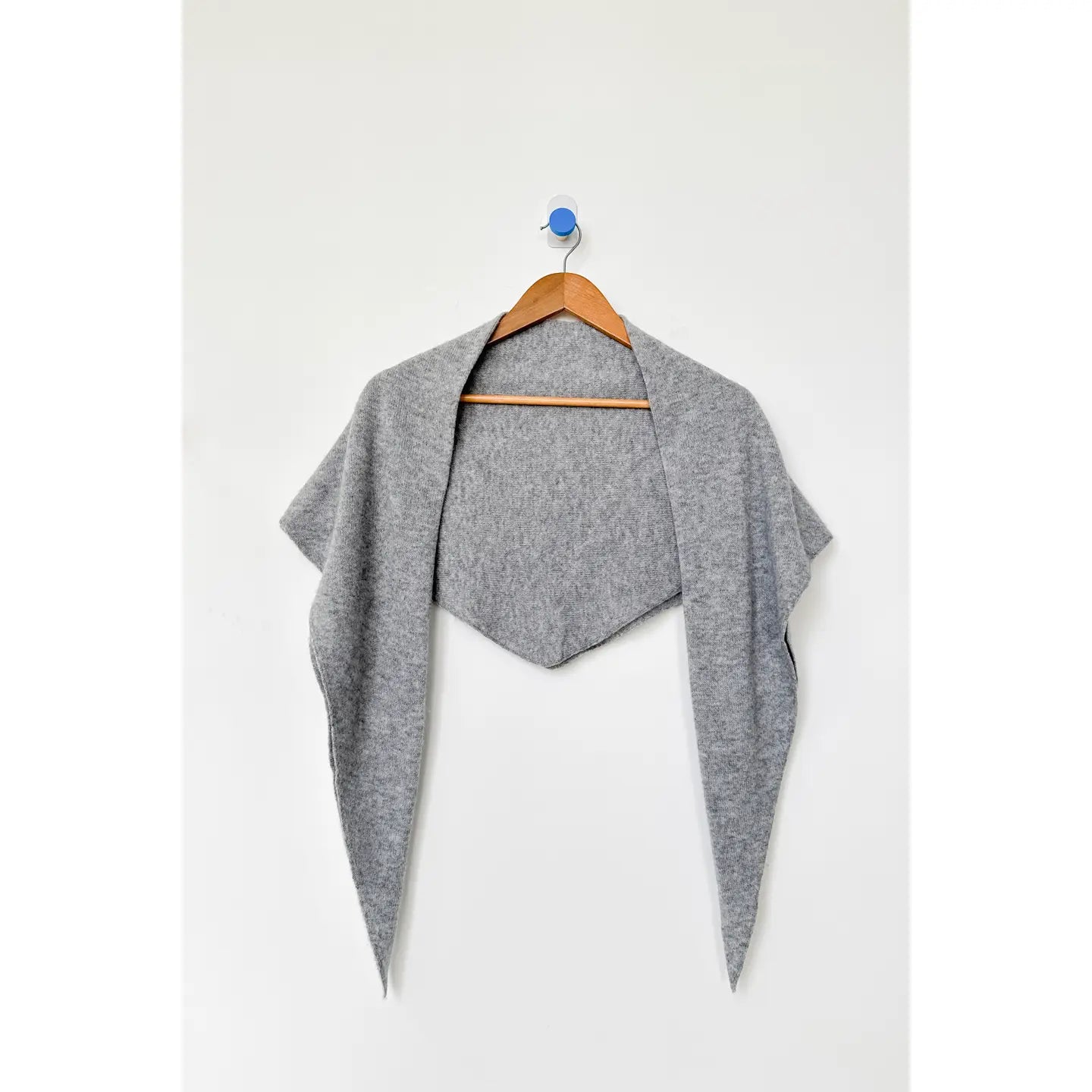 Gray cardigan on a wooden hanger against a white background