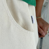 Close-up of a beige garment with a label, green sleeve visible