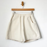 Beige shorts on a wooden hanger against a white background