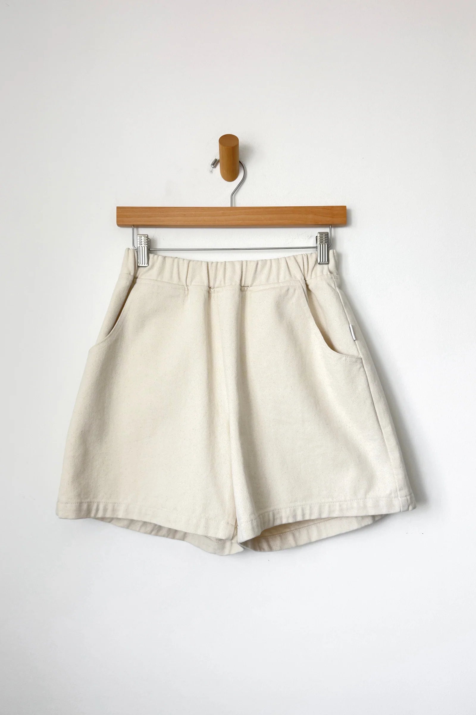 Beige shorts on a wooden hanger against a white background