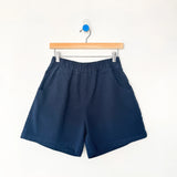 Navy blue shorts hanging on a wooden hanger against a white background