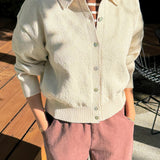 Person wearing a light-colored cardigan and pink pants outdoors.