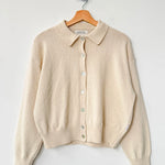 Beige cardigan on a wooden hanger against a white background