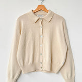 Beige cardigan on a wooden hanger against a white background