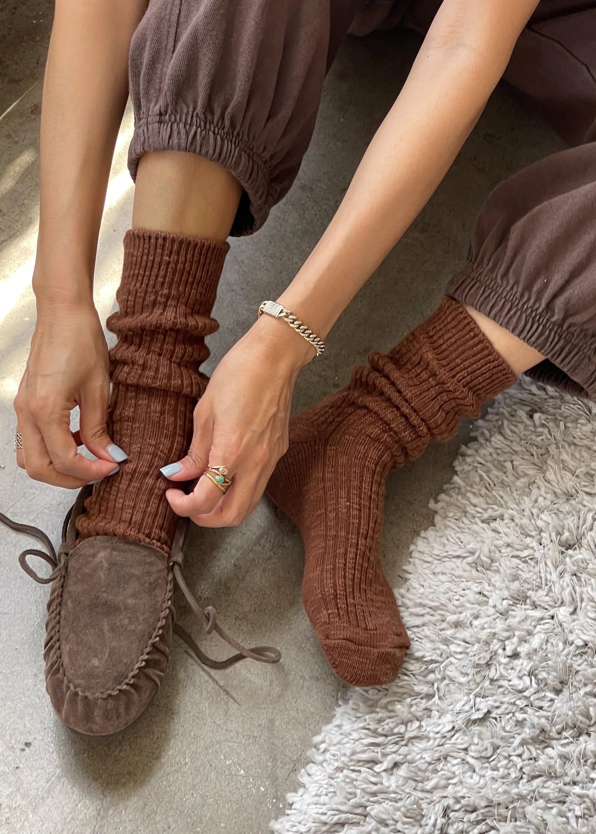 Person wearing brown ribbed socks and moccasins on a textured surface