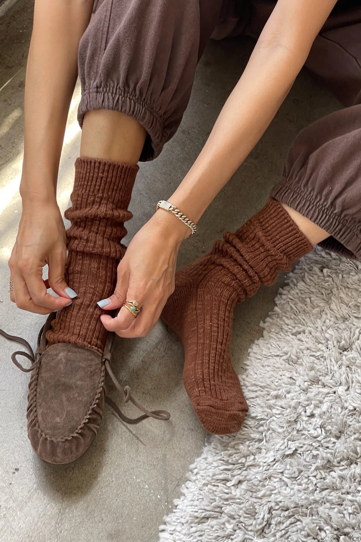 Person wearing brown ribbed socks and moccasins on a textured surface