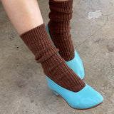 Brown leg warmers over blue shoes on a concrete floor