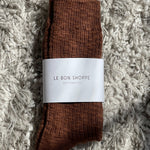 Brown socks with a white label on a textured gray surface