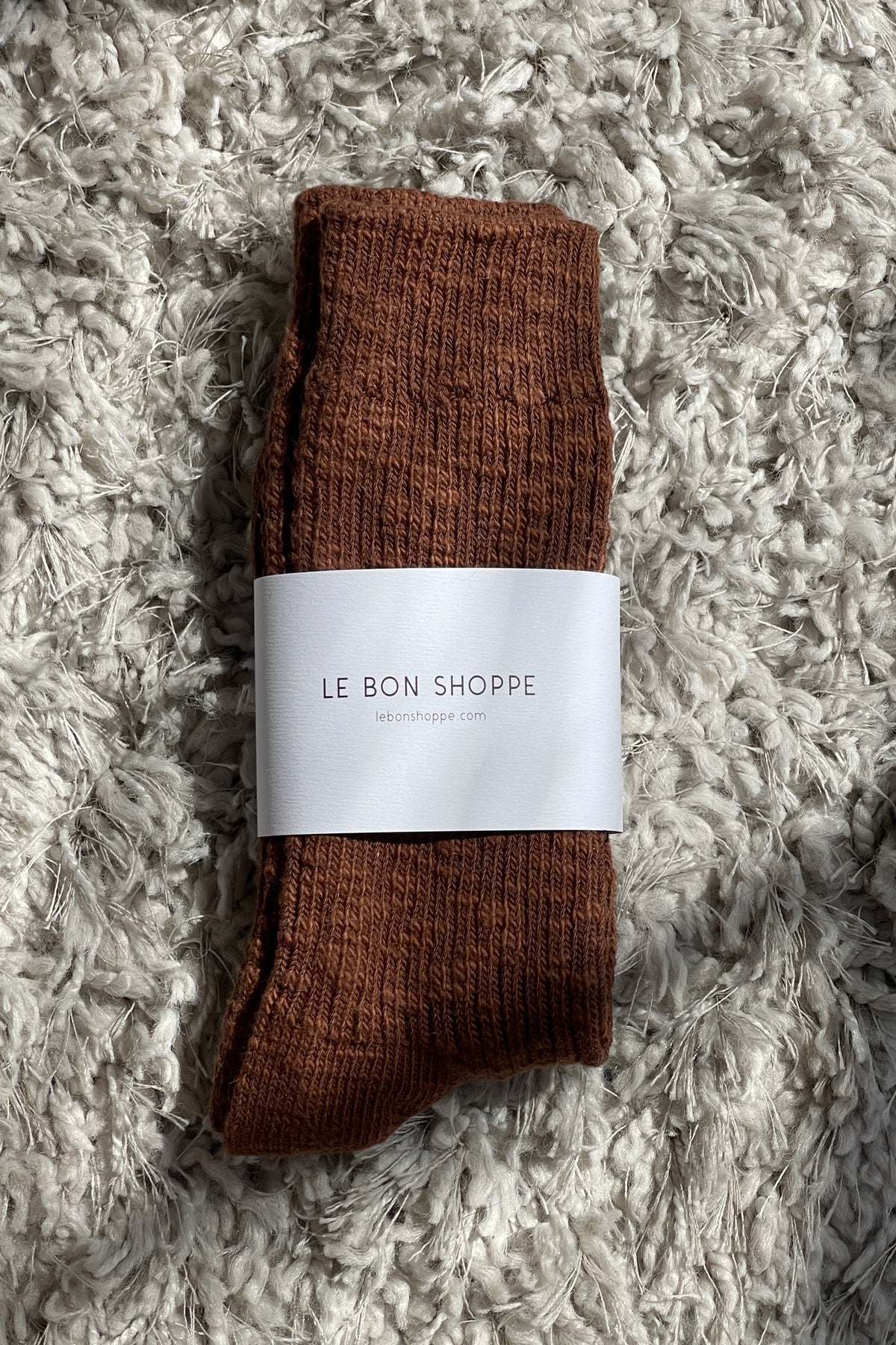 Brown socks with a white label on a textured gray surface