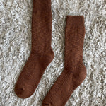 Pair of brown socks on a textured beige surface
