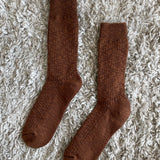 Pair of brown socks on a textured beige surface