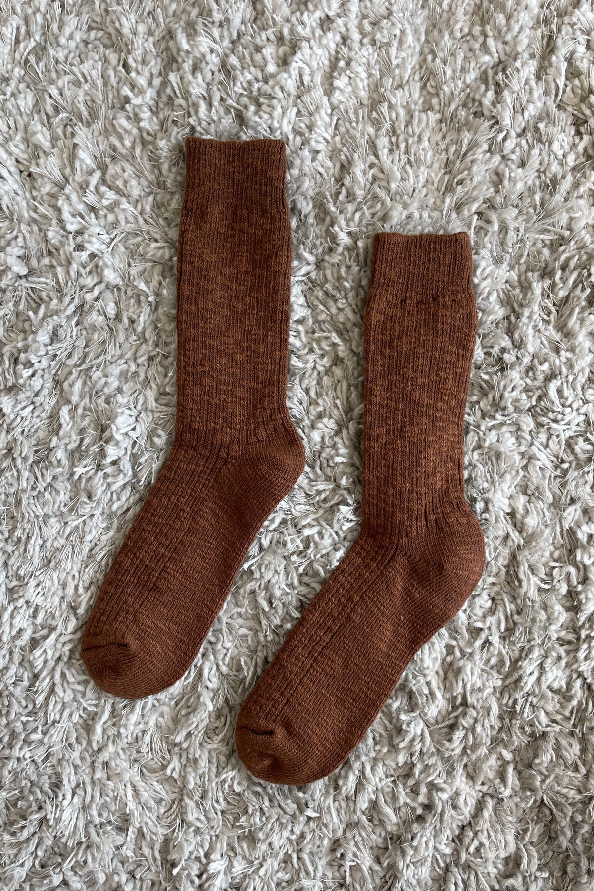Pair of brown socks on a textured beige surface
