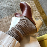 Brown leather shoes and socks on a textured floor