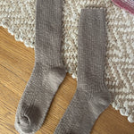 Pair of taupe socks on a textured rug