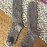 Pair of taupe socks on a textured rug