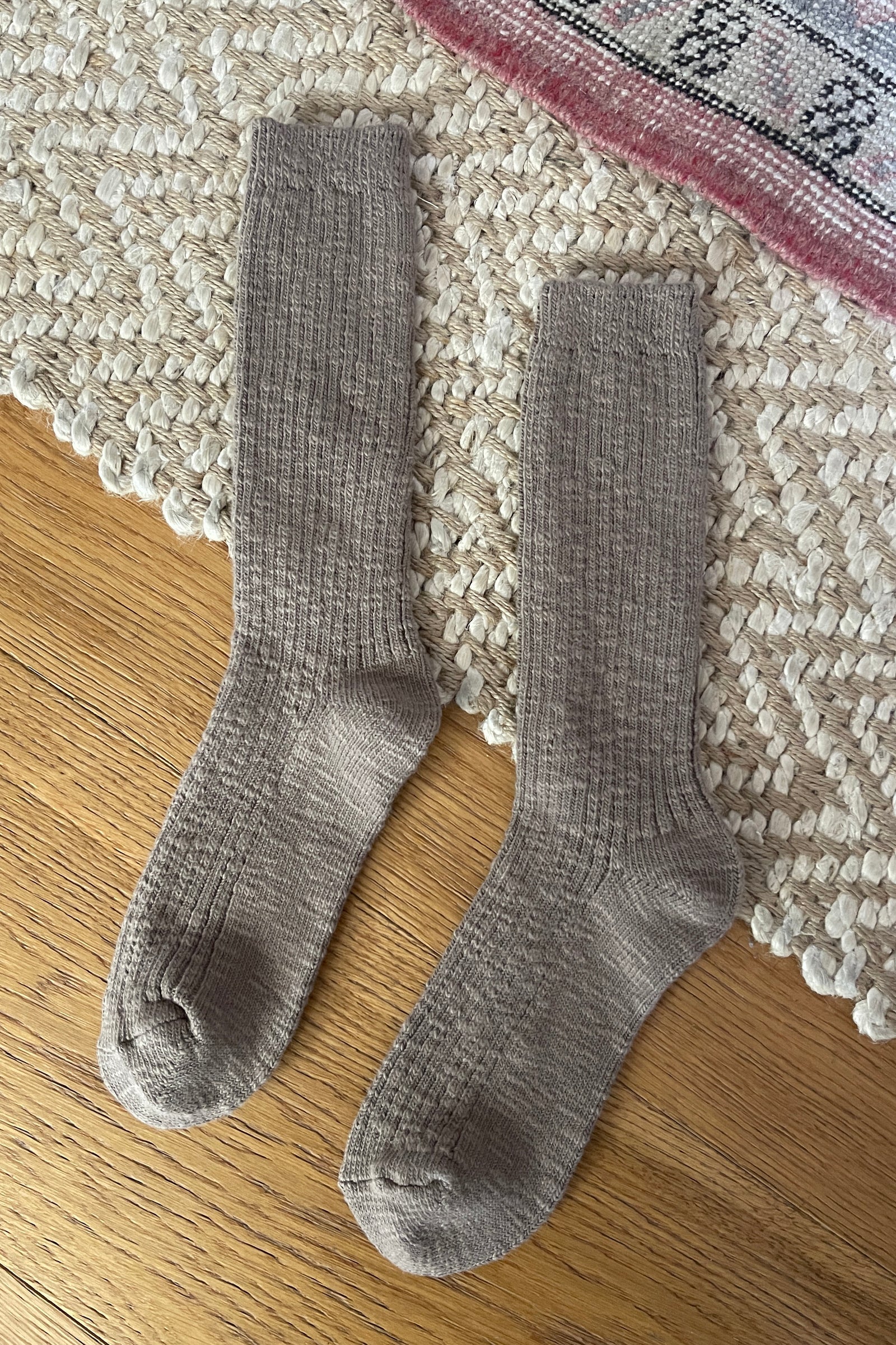 Pair of taupe socks on a textured rug