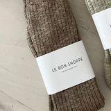 Brown sock with 'Le Bon Shoppe' label on a light wooden surface
