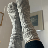 Gray knitted socks being worn indoors with a neutral background