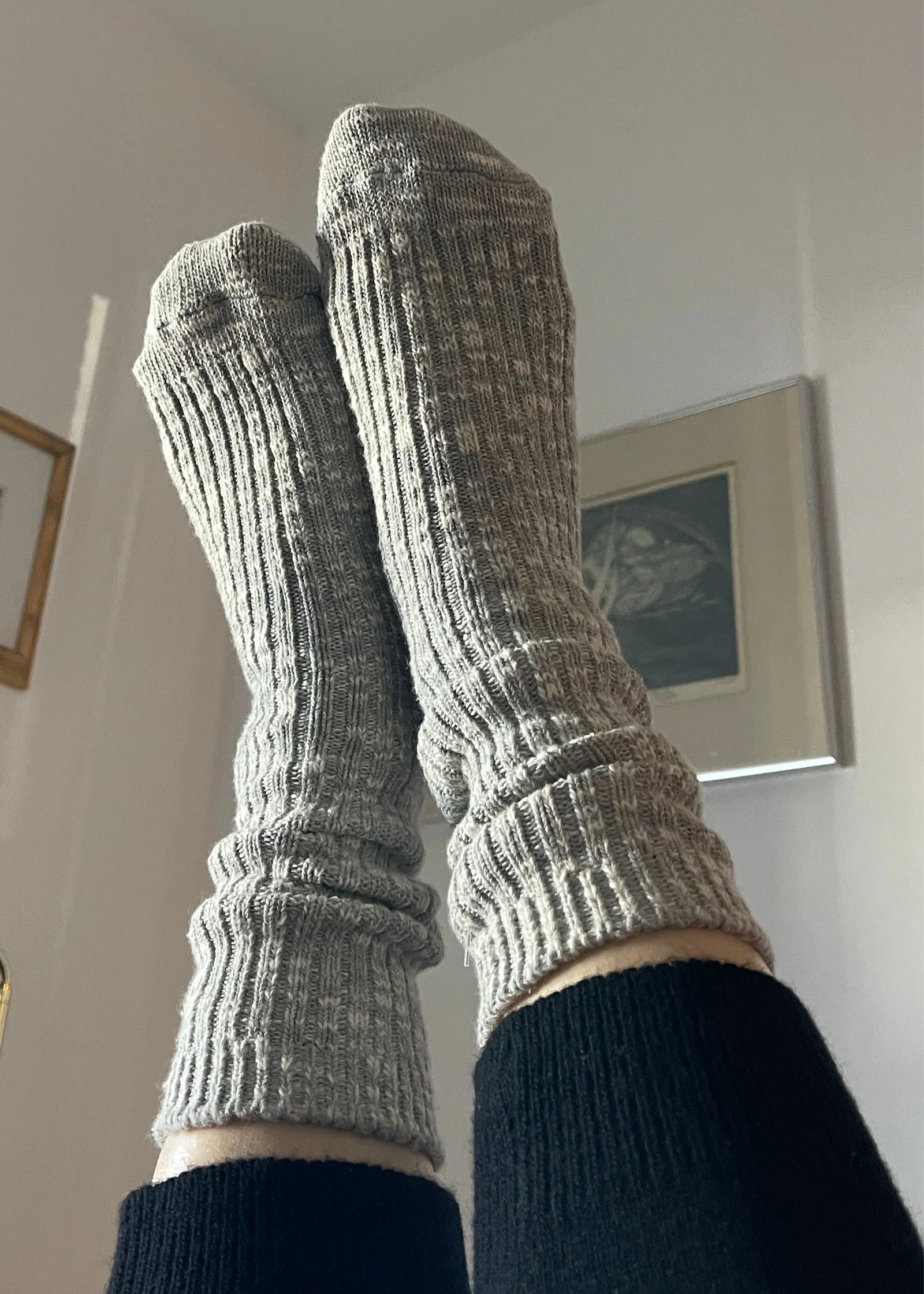 Gray knitted socks being worn indoors with a neutral background