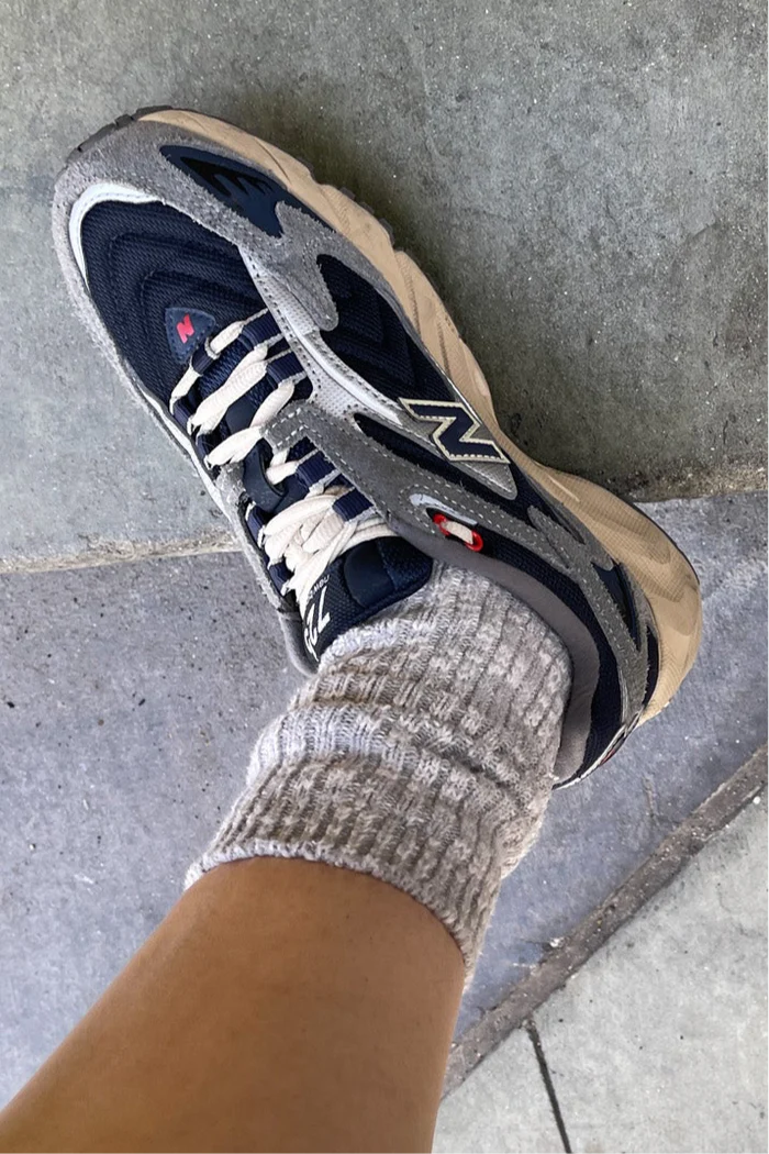 Gray and black sneaker with a brand logo worn on a concrete surface