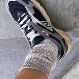 Gray and black sneaker with a brand logo worn on a concrete surface