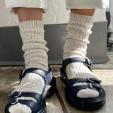Person wearing navy sandals with white socks on a concrete floor.