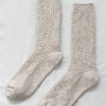 Pair of beige socks on a light gray background