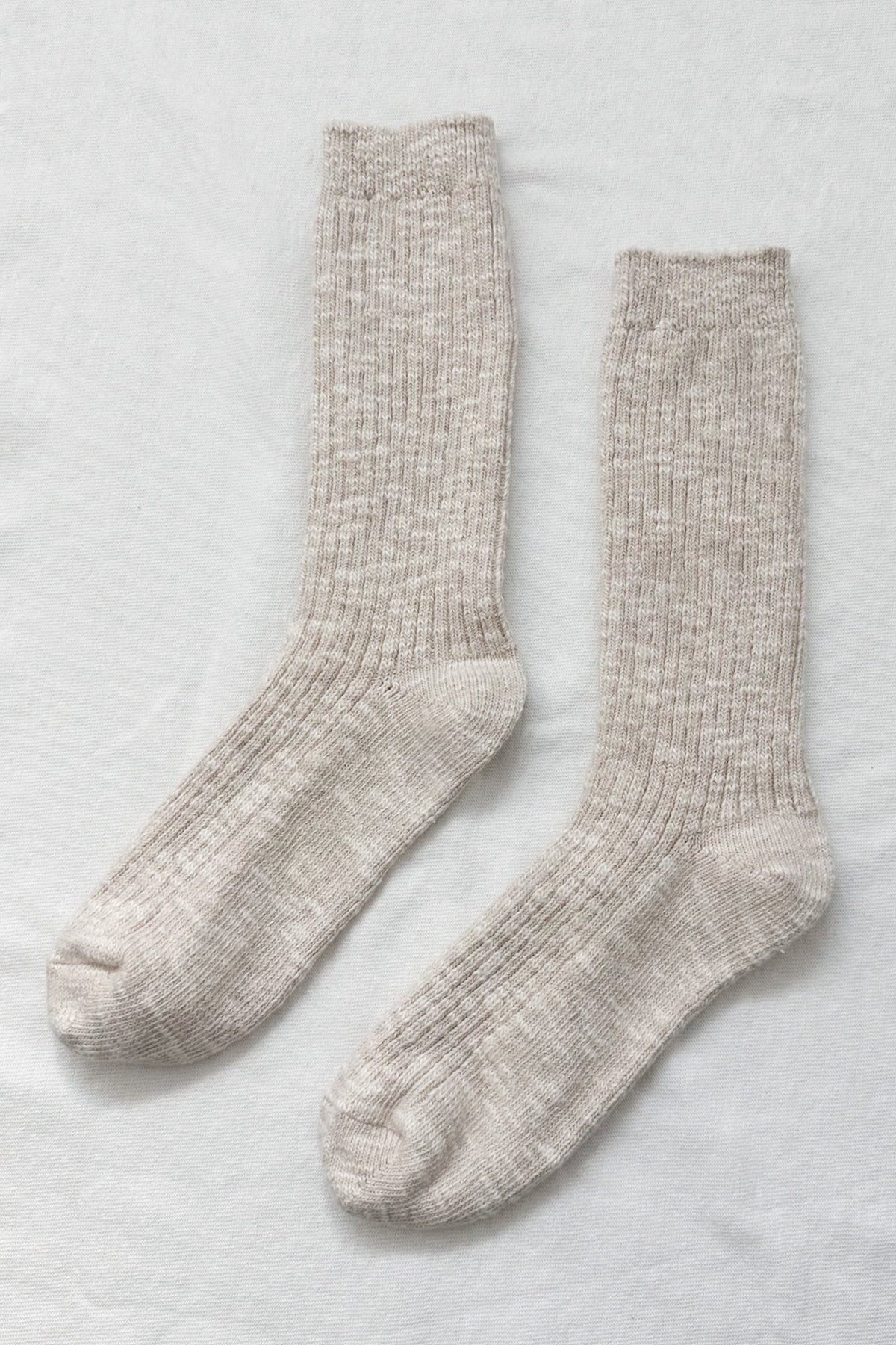 Pair of beige socks on a light gray background