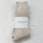 Pair of beige socks with a white label on a light gray background