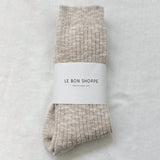 Pair of beige socks with a white label on a light gray background