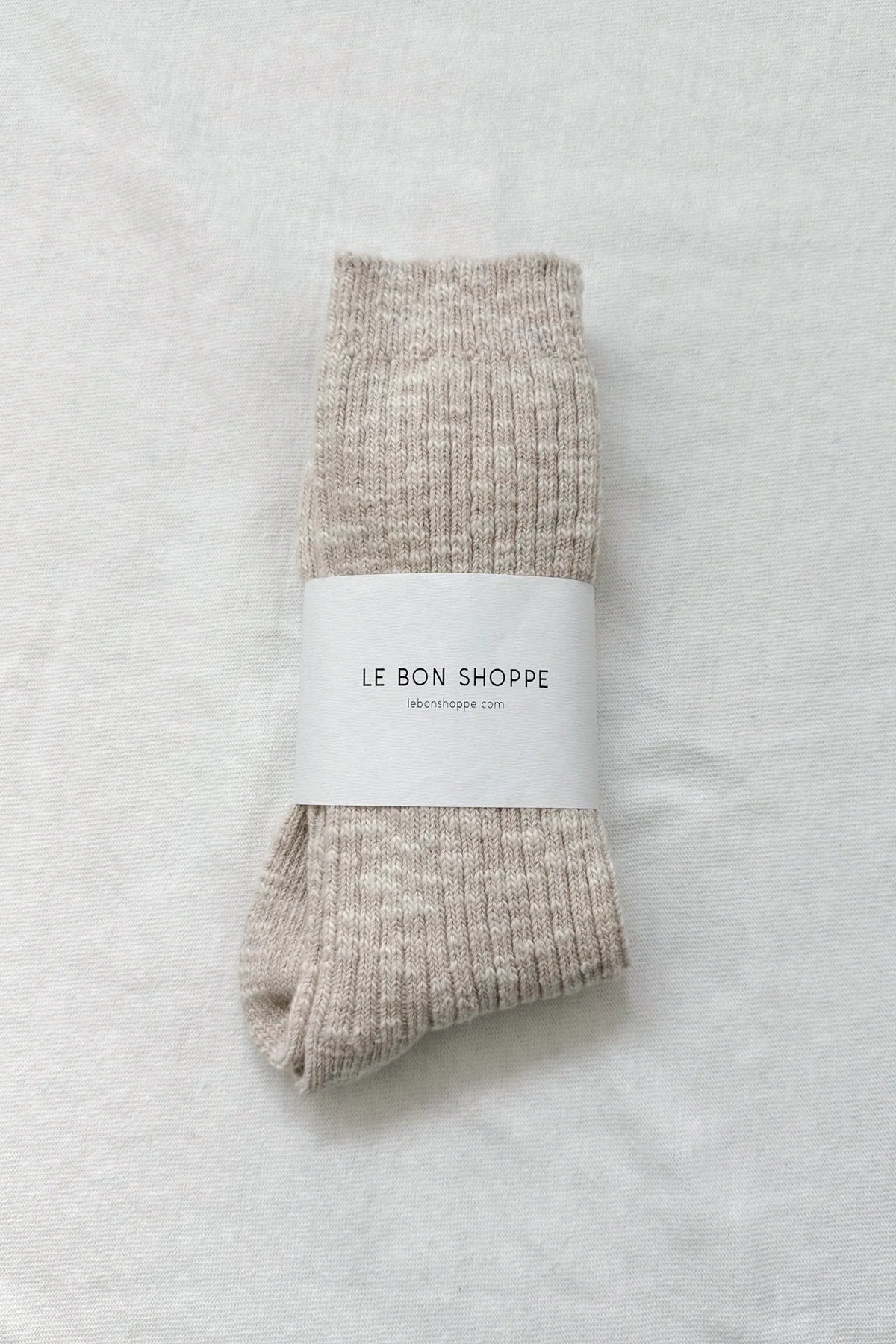 Pair of beige socks with a white label on a light gray background