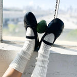 Person wearing black shoes and white socks on a swing with a blurred background