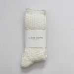 Packaged sock with 'Le Bon Shoppe' label on a gray background